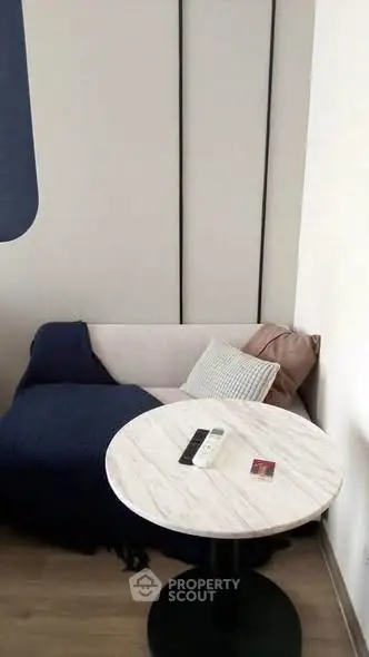 Cozy living room corner with modern sofa and round marble table, perfect for relaxation.
