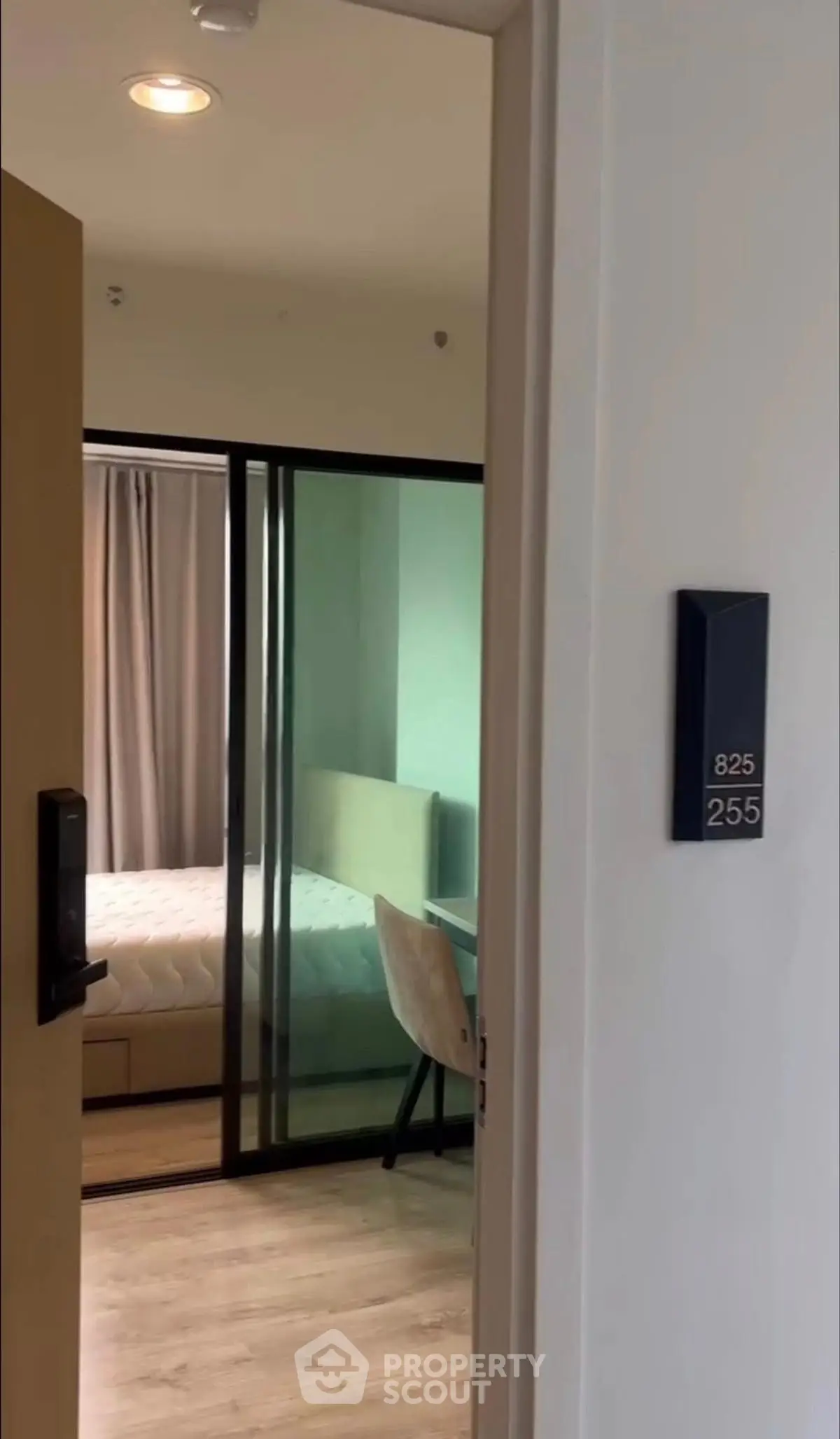 Modern apartment entrance with view into a stylish bedroom featuring glass sliding doors and contemporary decor.