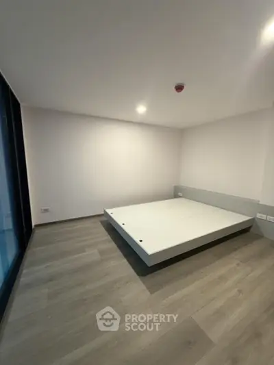 Spacious minimalist bedroom with modern flooring and large window