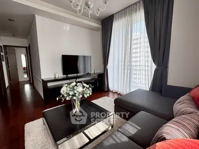 Elegant living room with modern decor, large TV, and natural light from balcony.