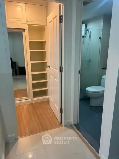 Modern apartment hallway with built-in storage and bathroom access, featuring sleek design and practical layout.