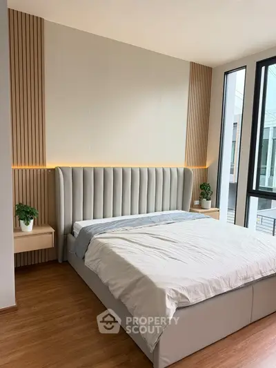 Modern bedroom with stylish headboard and large windows offering natural light.