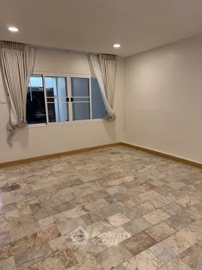 Spacious empty room with marble flooring and large window, ideal for customization.