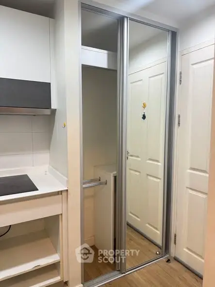 Modern apartment interior with sleek kitchen and mirrored closet doors.