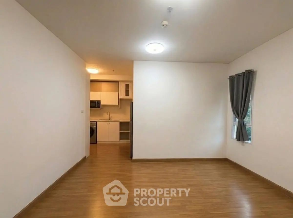 Spacious living room with wooden flooring and modern kitchen in open layout apartment.