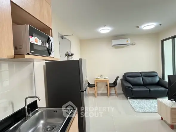 Modern open-plan living room and kitchen with sleek appliances and cozy seating area.