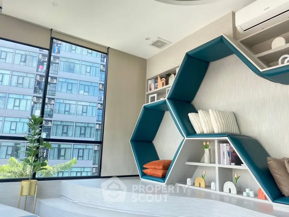 Modern living room with unique geometric shelving and large windows in a high-rise apartment.