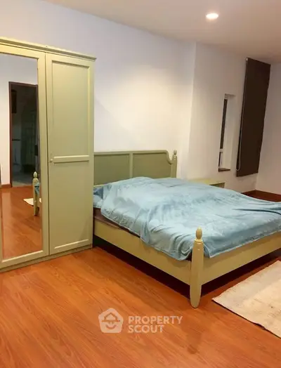 Cozy bedroom with wooden flooring and mirrored wardrobe