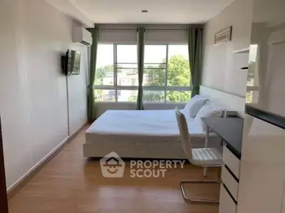 Spacious bedroom with large windows and modern furnishings in a bright apartment.