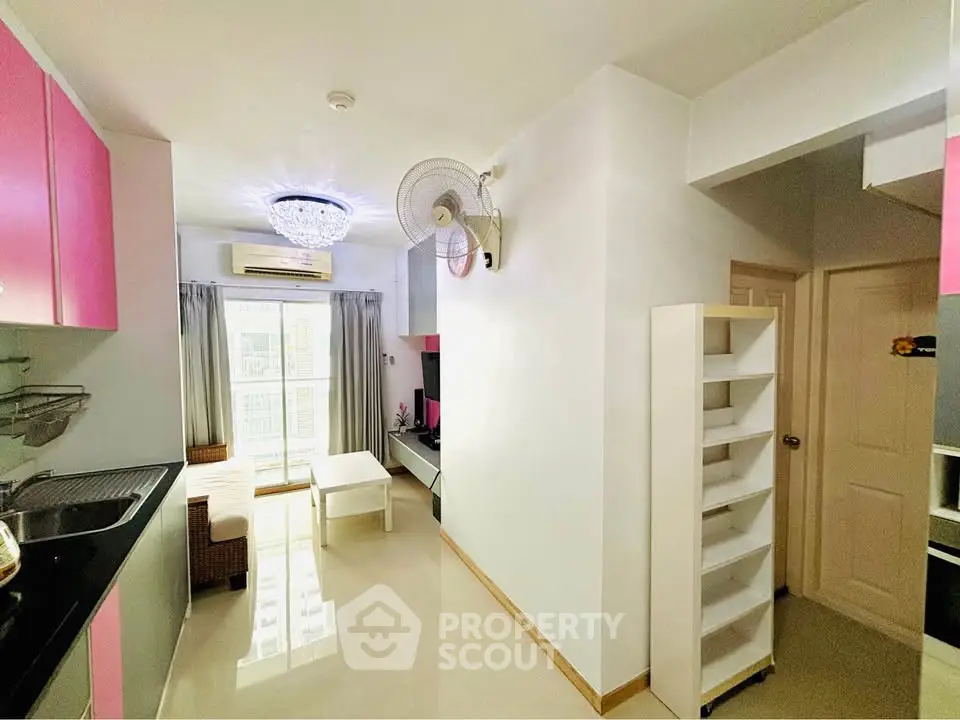 Bright and modern living space with pink kitchen cabinets and cozy seating area.
