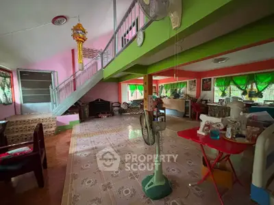 Spacious living room with colorful decor and open layout, featuring a staircase and vibrant green accents.