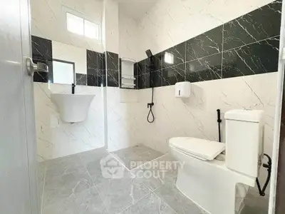 Modern bathroom with sleek design, featuring a wall-mounted sink and stylish black and white tiles.