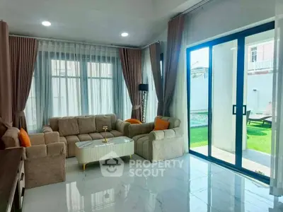 Elegant living room with modern furniture and large windows opening to a lush garden view.