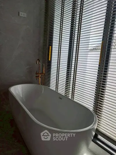 Luxurious bathroom with modern freestanding bathtub and stylish blinds.