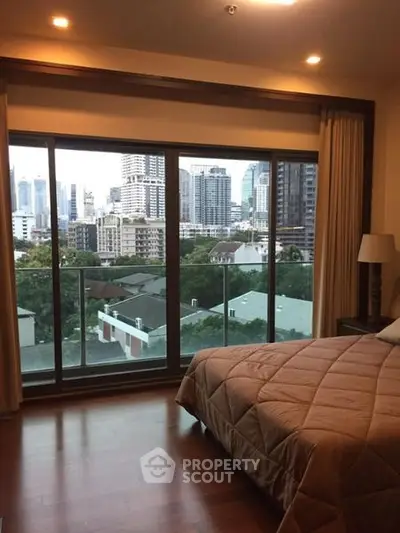 Luxurious bedroom with stunning city view and floor-to-ceiling windows in modern apartment.