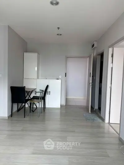 Spacious modern apartment interior with light wood flooring and minimalist furniture.