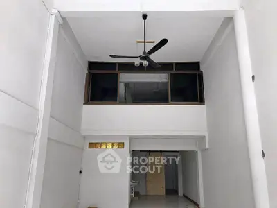 Spacious interior with high ceiling and modern fan, ideal for versatile living space.