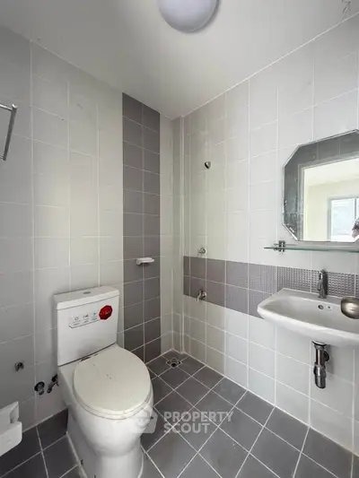Modern bathroom with sleek tiles and contemporary fixtures in a real estate property.