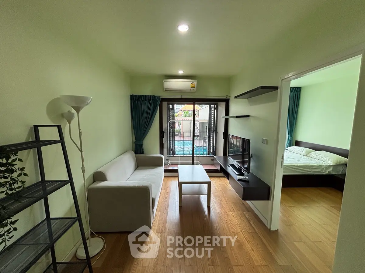 Modern living room with balcony view, featuring sleek furniture and natural light.