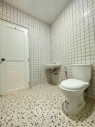 Modern minimalist bathroom with white tiled walls and terrazzo flooring.