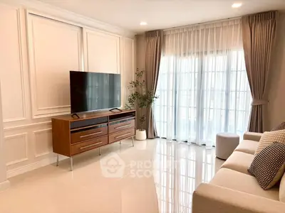 Elegant living room with modern TV stand, plush sofa, and floor-to-ceiling windows with sheer curtains.