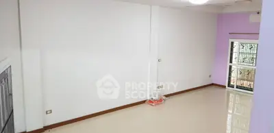 Spacious empty room with glossy tiled floor and large window for natural light.