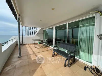 Spacious balcony with ocean view and outdoor seating in modern apartment