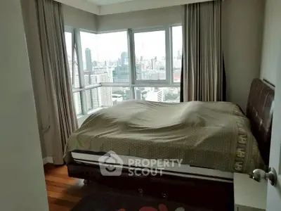 Spacious bedroom with panoramic city views and large windows in a modern apartment.