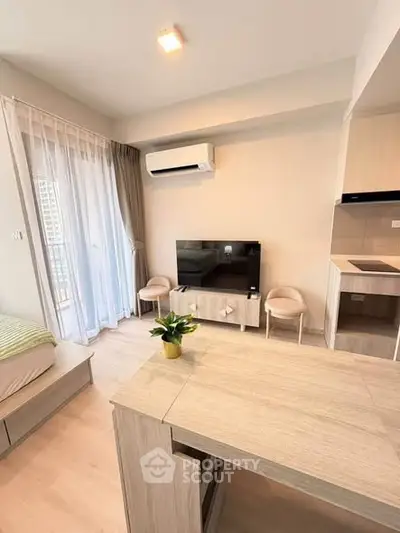 Modern living room with sleek furniture and natural light, featuring a TV and air conditioning unit.