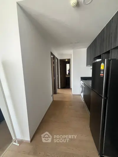 Modern apartment hallway with sleek kitchen appliances and wooden flooring