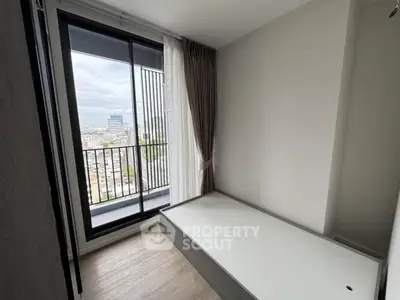 Compact bedroom with city view and sliding glass door to balcony