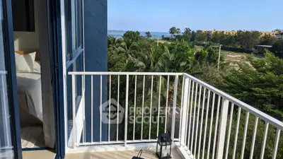 Stunning balcony view with lush greenery and ocean horizon, perfect for relaxation.