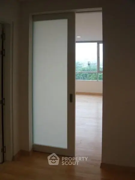 Modern interior with sliding frosted glass door and spacious room with large window view.