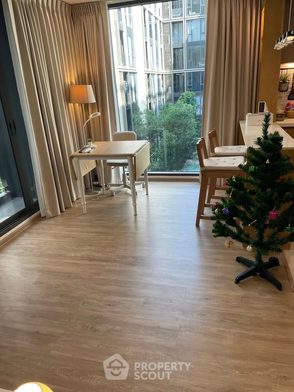 Modern living room with large windows, wooden flooring, and a cozy dining area, perfect for urban living.