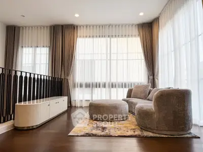 Elegant living room with modern furniture and large windows, featuring stylish curtains and a cozy seating area.
