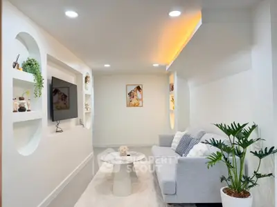 Modern living room with stylish decor, cozy gray sofa, and built-in TV unit, perfect for relaxation and entertainment.