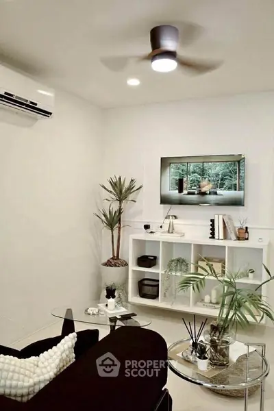 Modern living room with sleek black sofa, glass coffee table, and wall-mounted TV, perfect for stylish urban living.