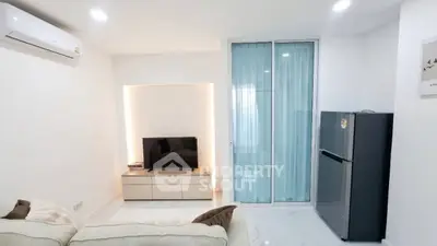 Modern living room with sleek design, featuring a cozy sofa, flat-screen TV, and a stylish refrigerator.