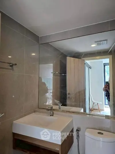 Modern bathroom with sleek fixtures and large mirror in contemporary home.