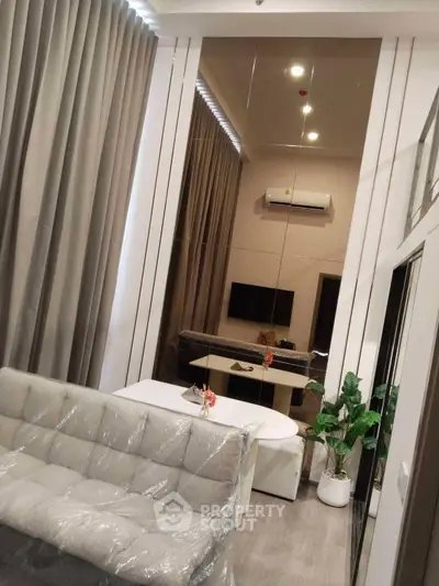 Modern living room with stylish decor, featuring a plush sofa, elegant dining area, and contemporary wall mirror.