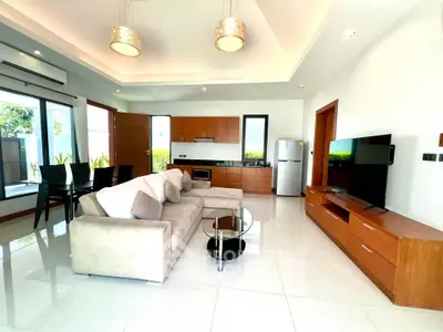 Spacious modern living room with open kitchen, elegant decor, and abundant natural light.
