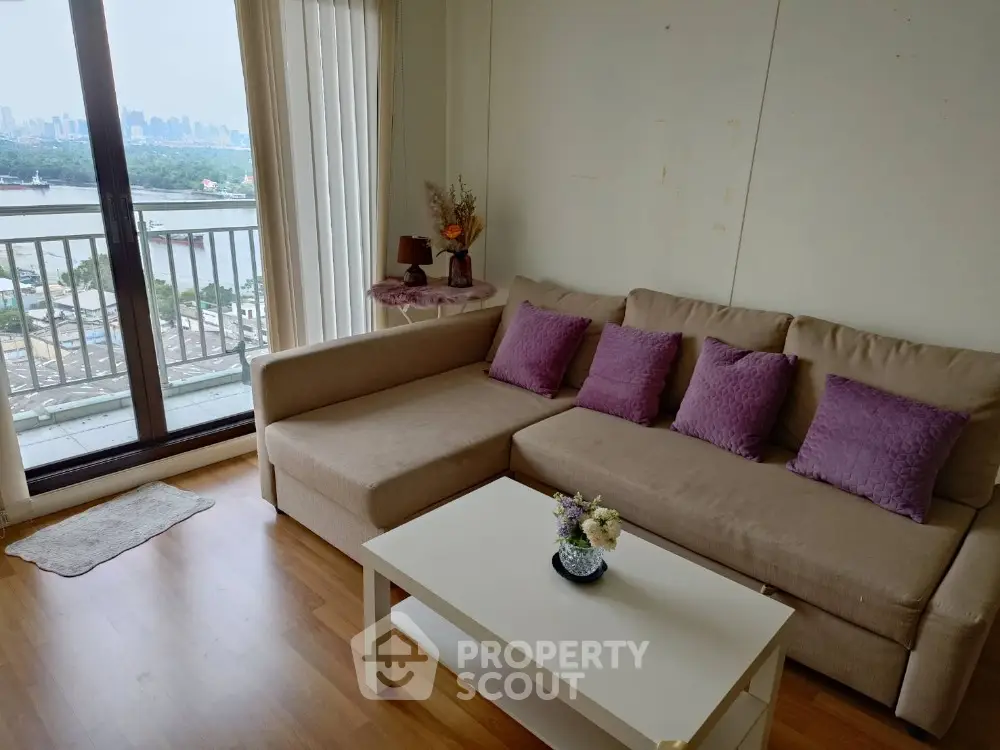 Chic living room with cozy beige sofa and vibrant purple cushions, offering a stunning city view from the balcony.