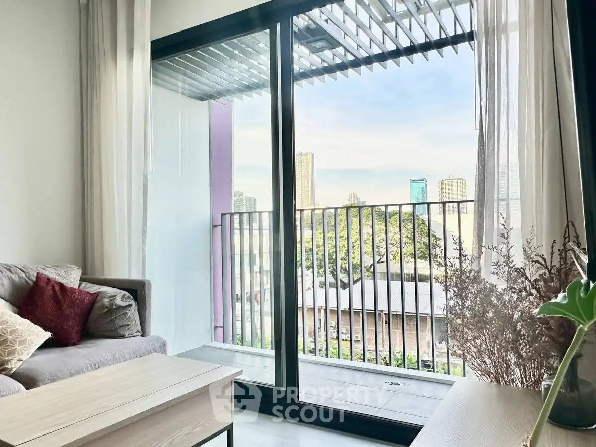 Modern living room with balcony view of city skyline, featuring cozy sofa and natural light.