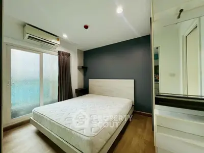 Modern bedroom with minimalist design, featuring a large window and air conditioning for comfort.