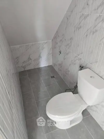 Modern minimalist bathroom with sleek tile design and compact layout.