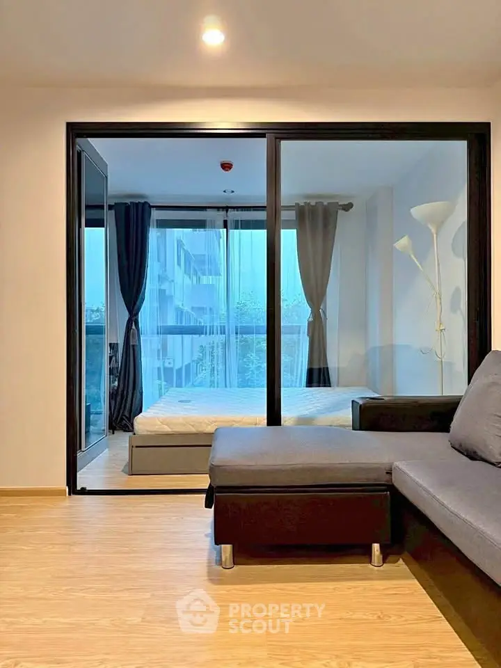 Modern apartment with glass partitioned bedroom and cozy living area, featuring floor-to-ceiling windows.