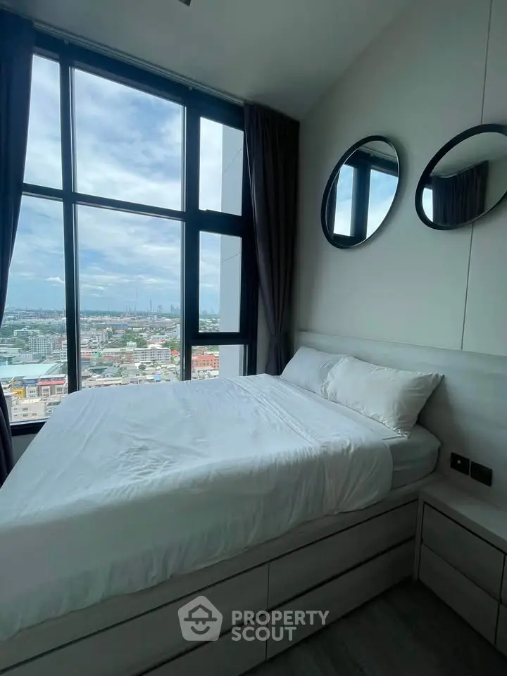 Modern bedroom with large windows offering stunning city views and stylish decor.