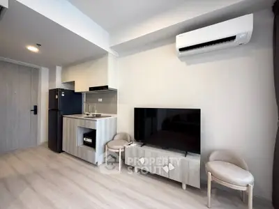 Modern apartment interior with compact kitchen and stylish living area featuring air conditioning and sleek furniture.
