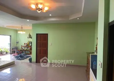 Spacious living room with green walls and modern lighting, perfect for family gatherings.