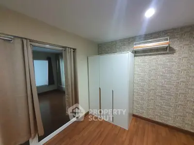 Spacious bedroom with wooden flooring and modern wardrobe
